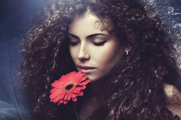 Woman with curly hair and a red flower
