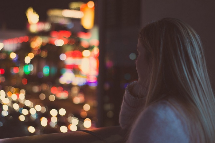 Woman looking at bokeh city lights at night