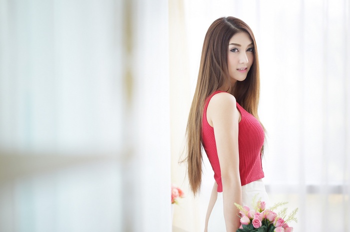Asian woman in red top holding pink flowers