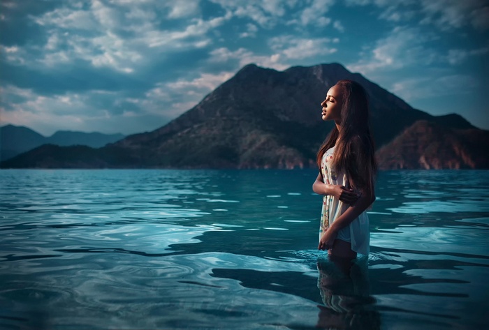Woman standing in the sea with mountains in the background