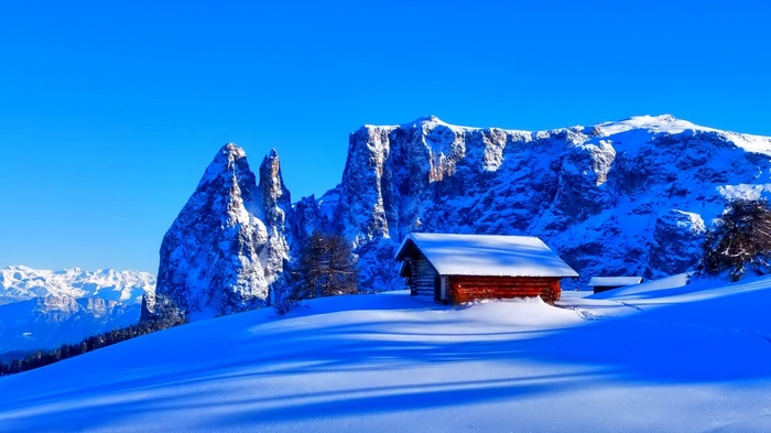 Snowy mountains with a small wooden cabin