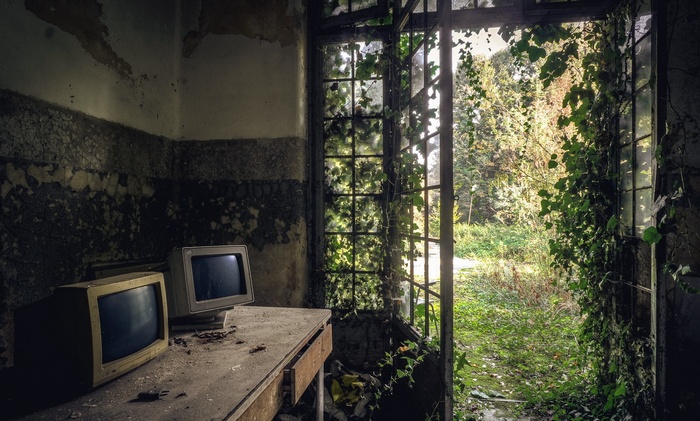 Abandoned room with old monitors and overgrown window