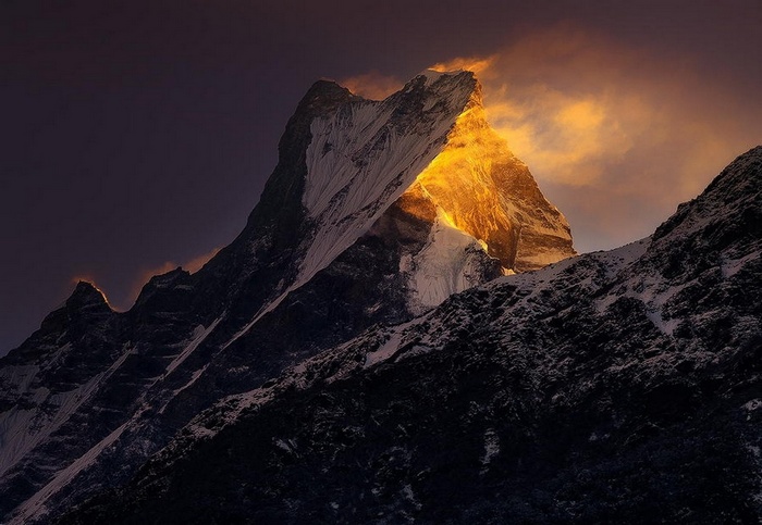Golden sunlight illuminates a snowy Himalayan mountain peak