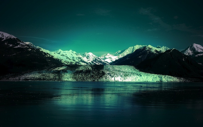 Glacier and snow-capped mountains reflected in dark water
