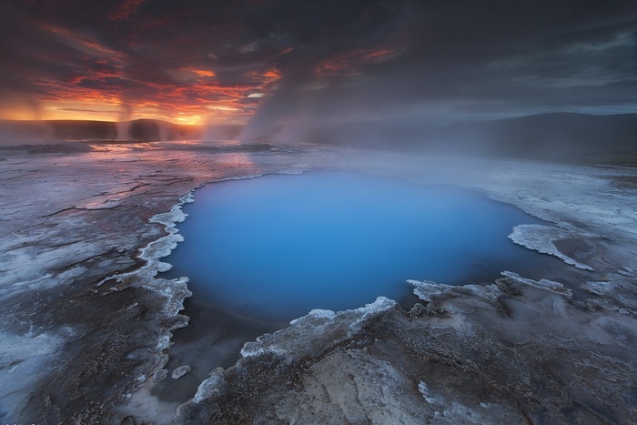 Blue hot spring in Iceland at sunset with steam