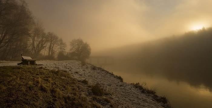 Bench by a misty lake at sunrise