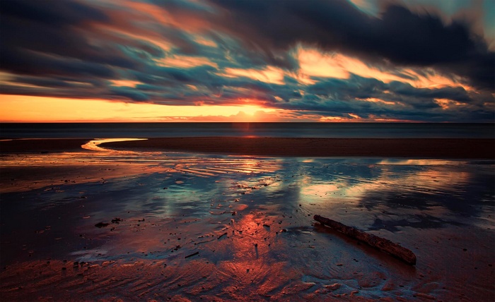 Sunset over the sea at a beach with dramatic clouds