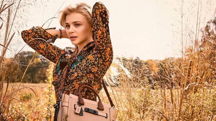 Chloë Grace Moretz in a field with a Coach bag