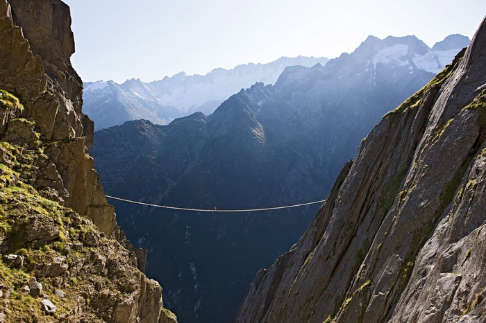 Person walking on a tightrope between mountains