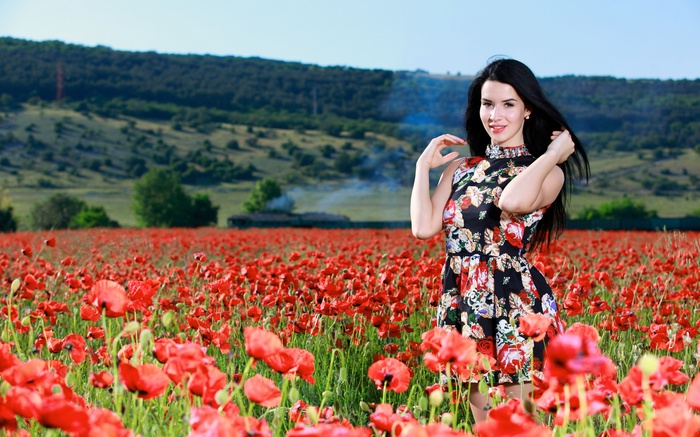 Woman with black hair in a poppy field