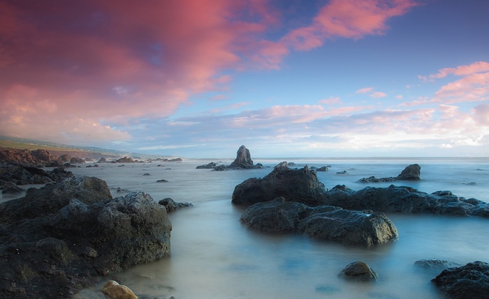 Rocky coast with pink clouds at sunset