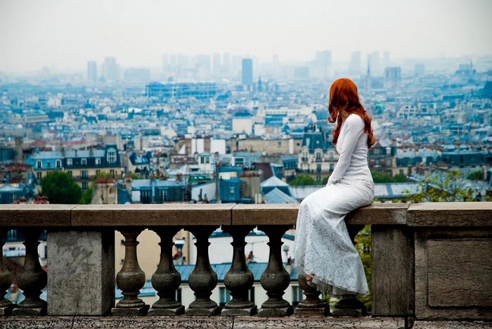 Woman in white dress on a balcony overlooking Paris