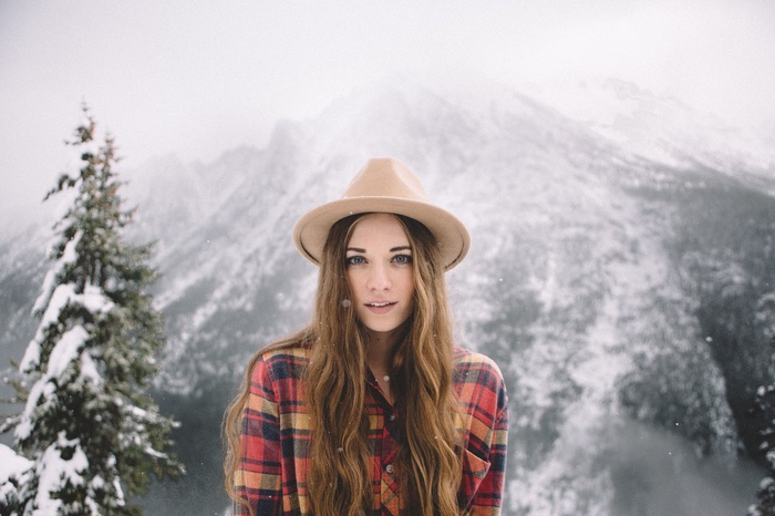 Woman in hat and plaid shirt in snowy mountains