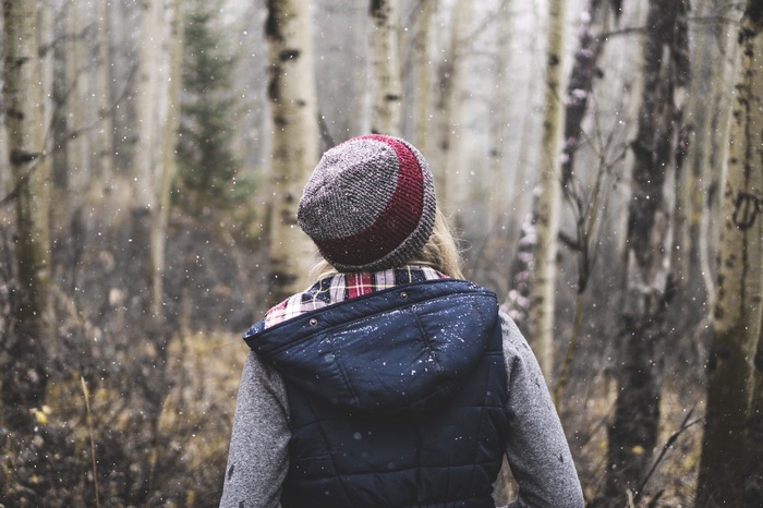 Woman in a hat and vest in a snowy forest