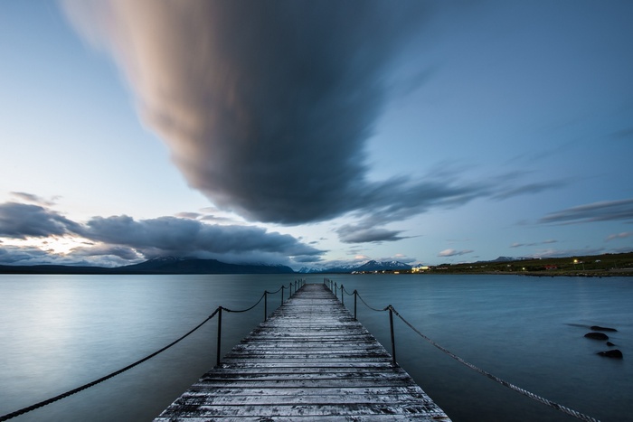 Puerto Natales pier at dusk with clouds over mountains