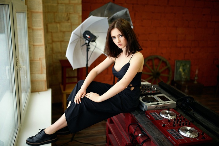 Woman in black dress sitting by DJ equipment