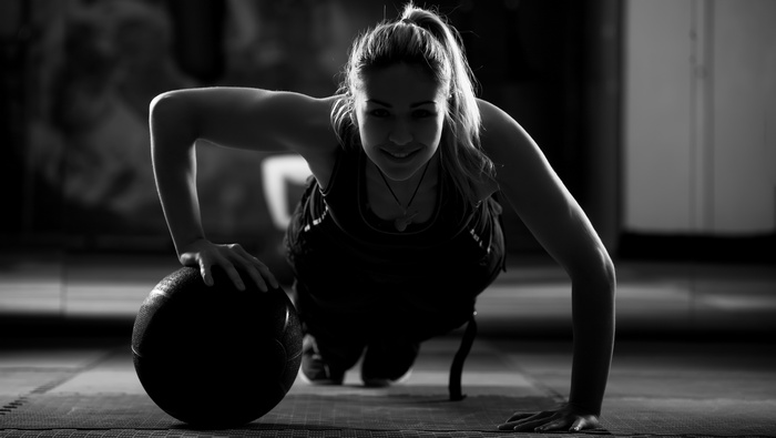 Woman doing push-ups with a medicine ball