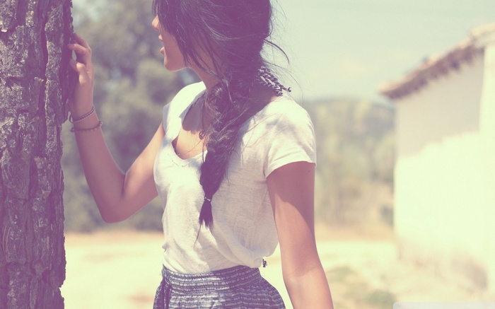 Woman with long hair leaning on a tree