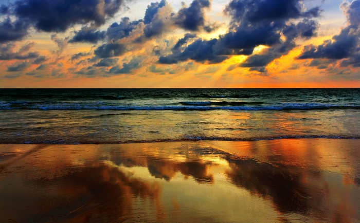 Sunset over the ocean with dramatic clouds and reflections