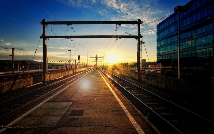 Train station tracks at sunset with modern building