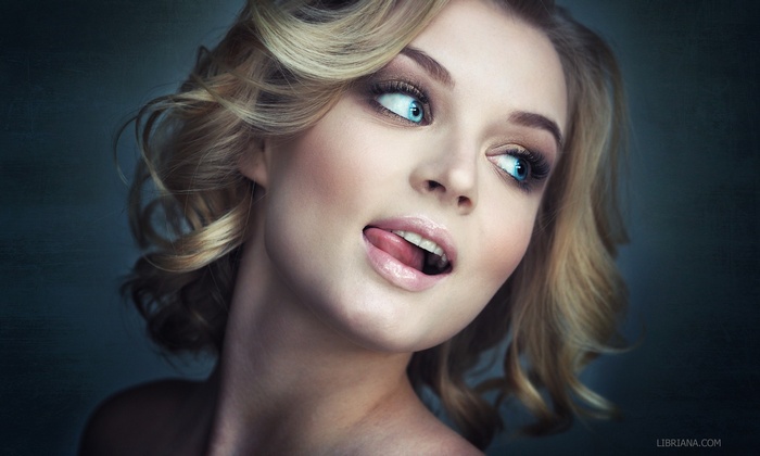 Woman with blonde hair and blue eyes sticking out her tongue