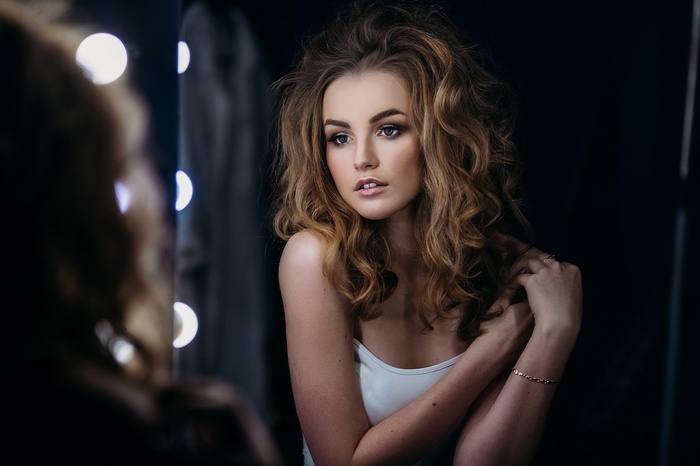 Julia Tavrina with curly blonde hair in front of a mirror