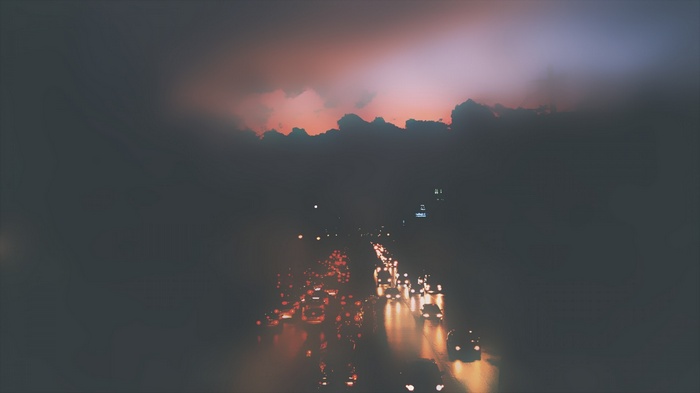 Traffic on a misty road at sunset