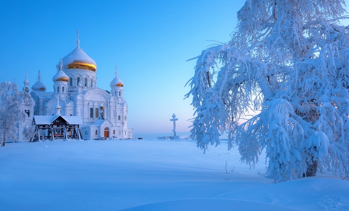 White church with golden domes in snowy Ural landscape