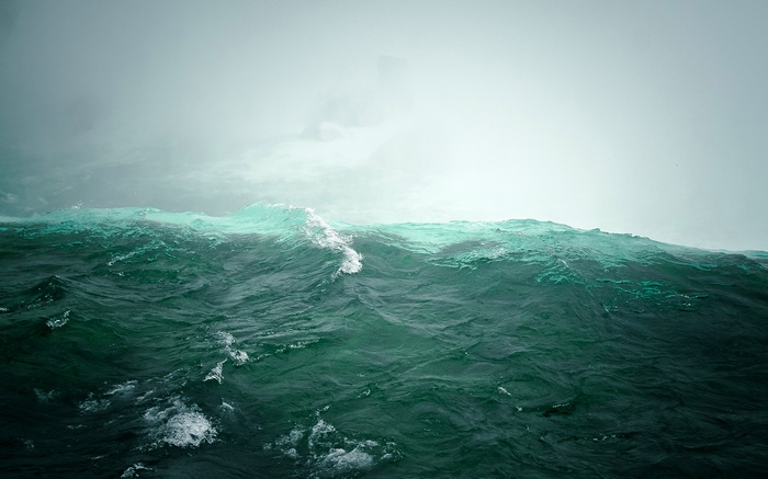 Turquoise waves crashing under a misty sky