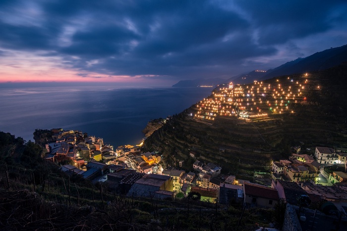 Manarola village illuminated at dusk with sea and clouds