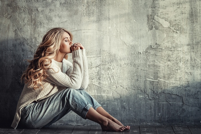 Liliya Nazarova sitting barefoot in jeans and sweater