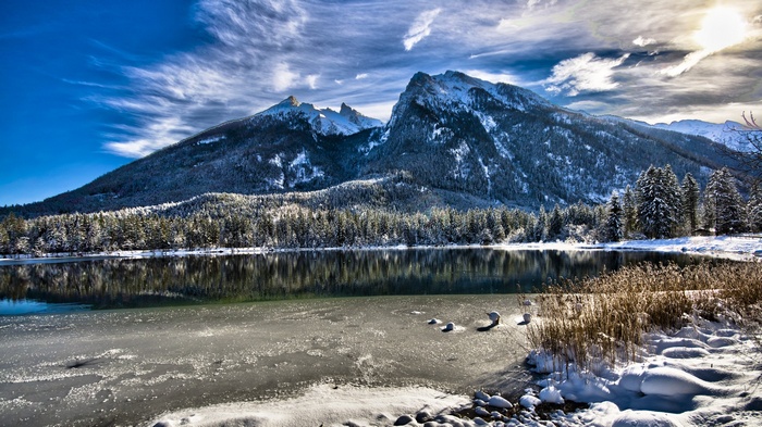 Snowy mountains reflected in a partially frozen lake