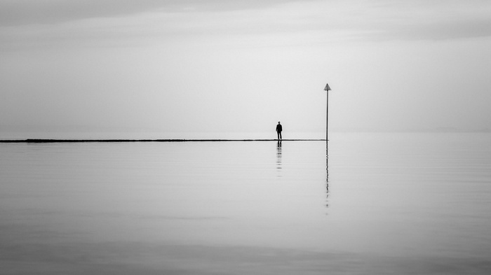 Man standing on a pier in the water with reflection