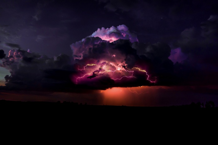 Lightning strikes through dark storm clouds at night