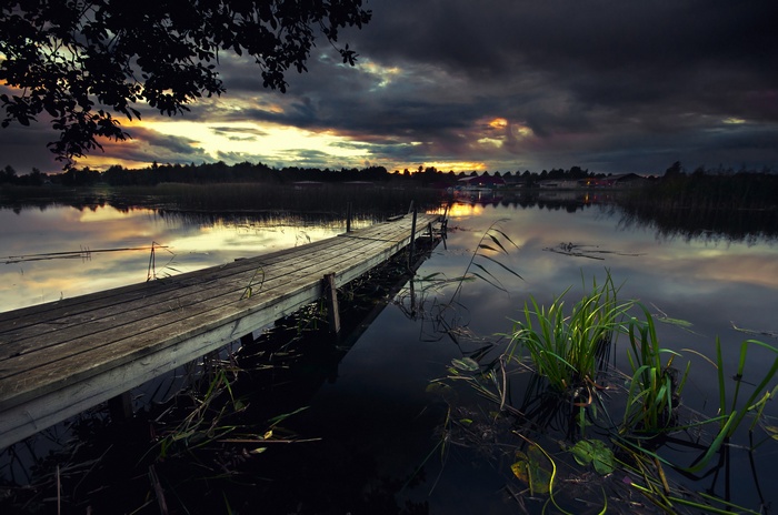 Wooden pier on a lake at sunset with dramatic clouds