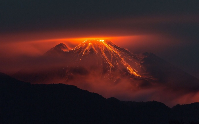 Volcano erupting with lava flowing down its slopes