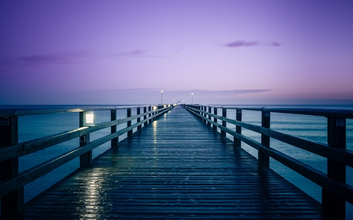 Wooden pier over the sea at dusk with purple sky