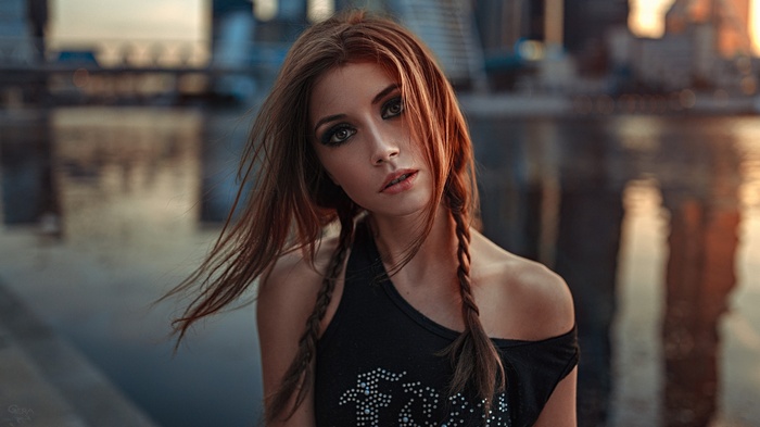 Portrait of Ksenia Kokoreva with braids and cityscape background