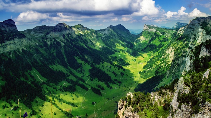 Green mountain valley with dramatic clouds and rocky peaks