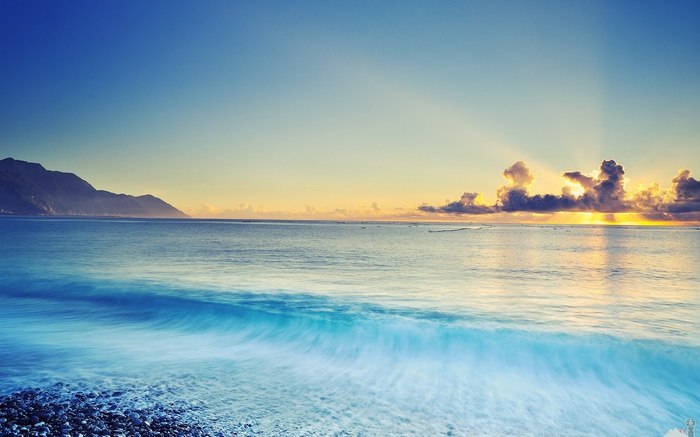 Ocean waves crashing on a pebble beach at sunrise