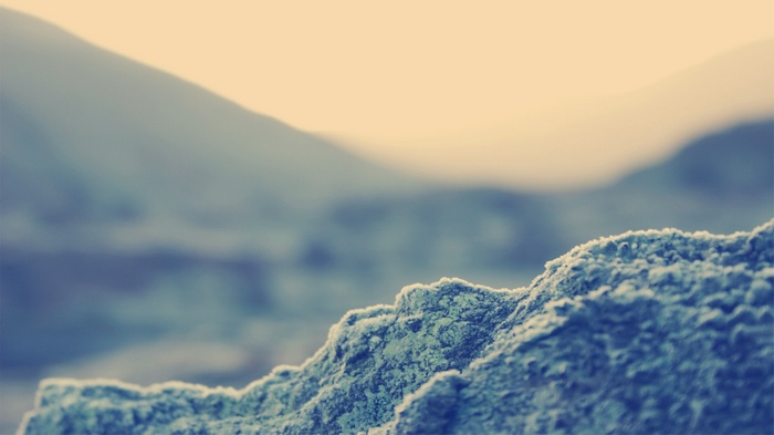Close-up of a frosted rock with blurred mountains in the background