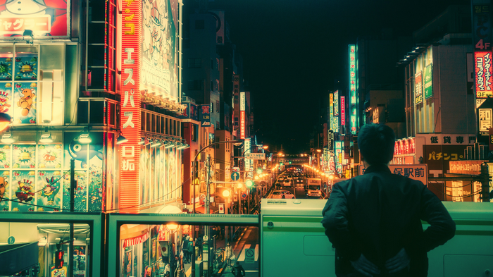 Man looking at neon signs in Tokyo street at night