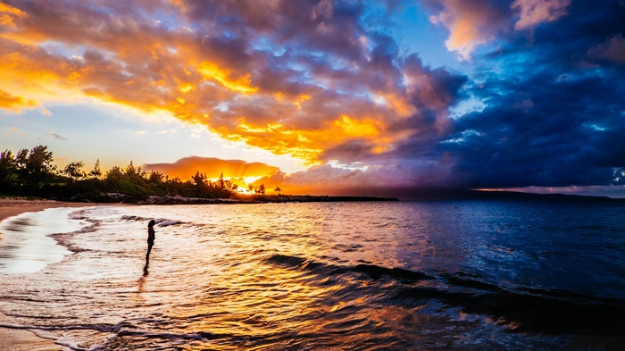 Sunset over the ocean with a person on the beach