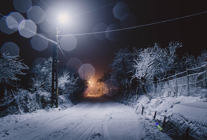 Snowy road at night under a street light