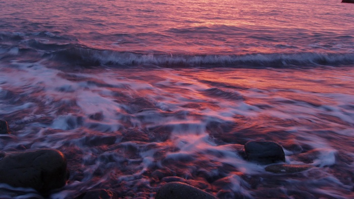 Ocean waves crashing on rocks at sunset
