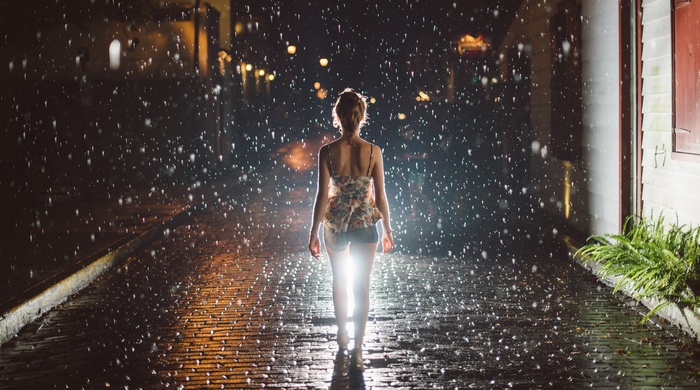 Woman walking in the rain at night