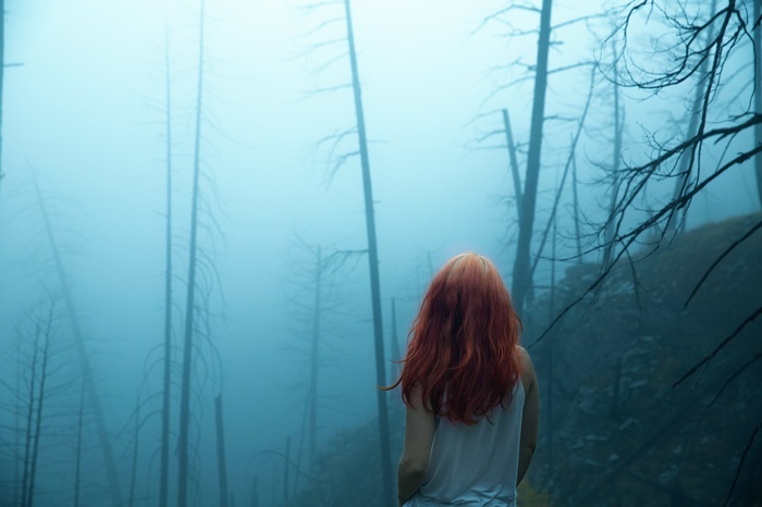 Woman with red hair in a misty forest
