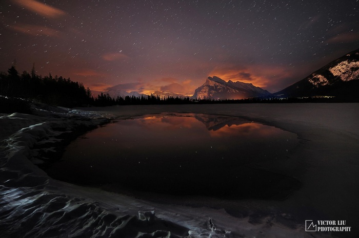 Night sky over mountains and frozen lake