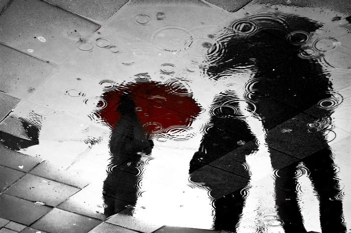 Reflections of people with umbrellas in the rain