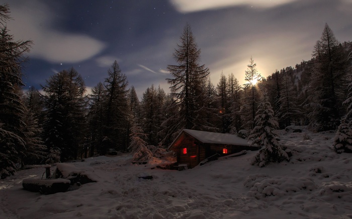 Winter cabin in a snowy forest at night